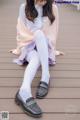 A woman sitting on a wooden floor wearing white tights.