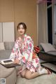 A woman in a kimono sitting on the floor holding a tablet.