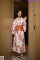 A woman in a kimono standing in front of a door.