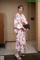 A woman in a kimono holding a black folder.