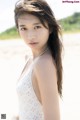 A woman in a white dress standing on a beach.