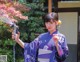 A woman in a kimono is holding a hose.