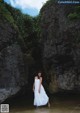 A woman in a white dress standing in the water.