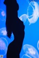 A silhouette of a woman standing in front of jellyfish.