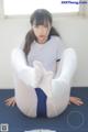 A woman sitting on top of a yoga mat with her legs crossed.