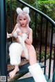 A woman in a white furry outfit sitting on a railing.