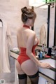 A woman in a red bodysuit and black stockings standing in front of a mirror.