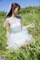 A woman in a wedding dress sitting in tall grass.