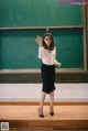 A woman standing in front of a blackboard in a classroom.