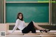 A woman sitting on a bench in front of a blackboard.