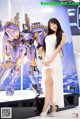 A woman in a white dress standing next to a giant robot.