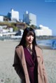 A woman standing on a beach next to the ocean.