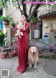 A woman in a red dress holding a dog.