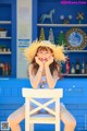 A woman sitting at a table with a straw hat on.